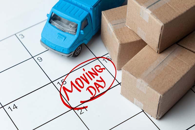 Moving day on the calendar is written in red. Calendar with a note with cardboard boxes and truck